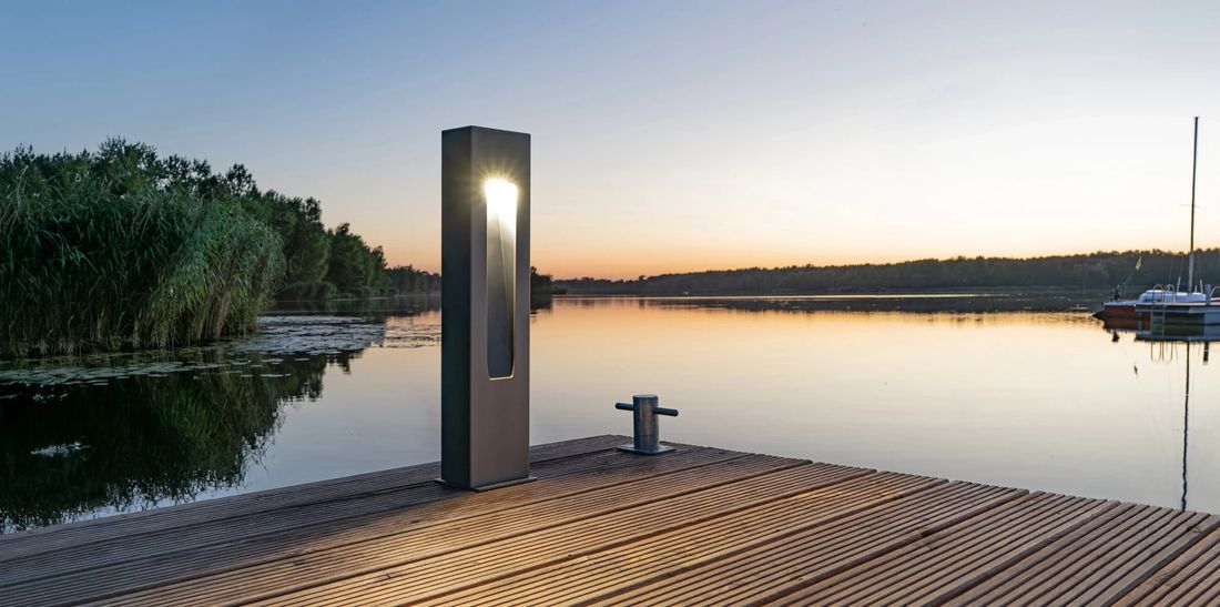 Borne aluminium Rosa SIMPLE CUT LED allumée au bord d’un ponton au coucher du soleil